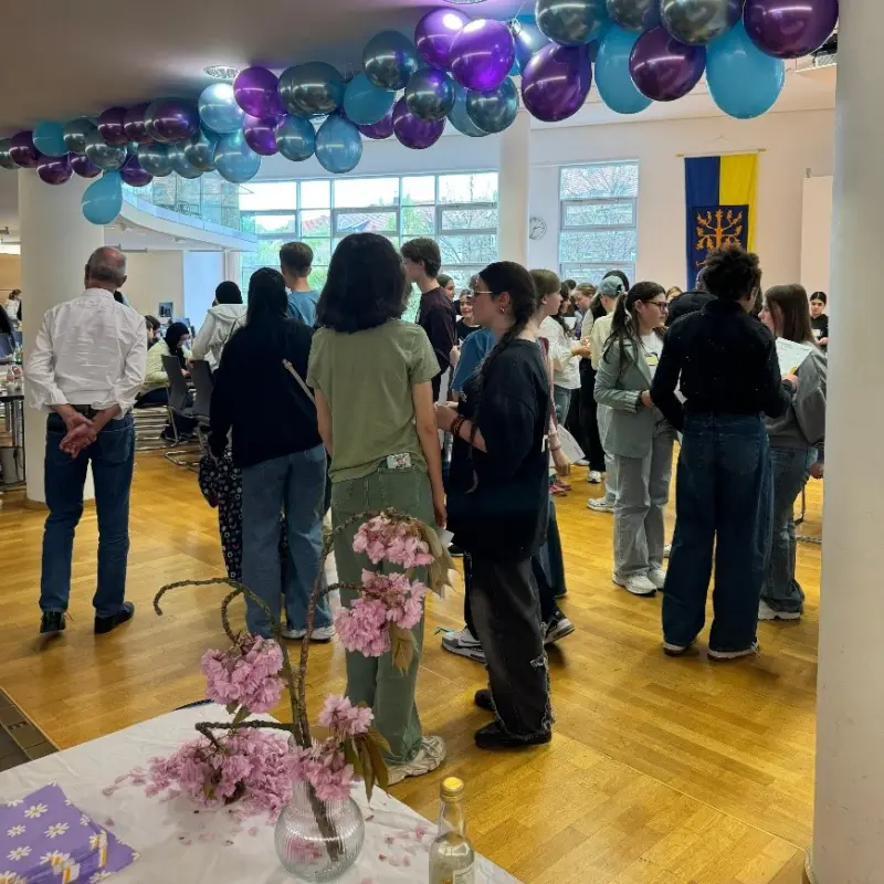 Foto: Im Ratssaal haben sich viele Jugendliche versammelt, die in kleineren Gruppen zusammenstehen und miteinander sprechen. Die Decke ist mit bunten Luftballons dekoriert.