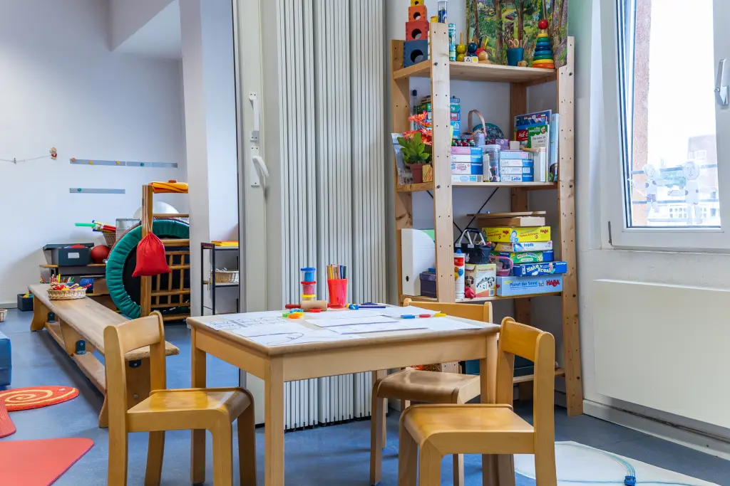 Ein Raum im Rathaus II der Stadt Hagen, es gibt viele Bücher und Spielzeuge. In der Mitte steht ein Tisch für Kinder.