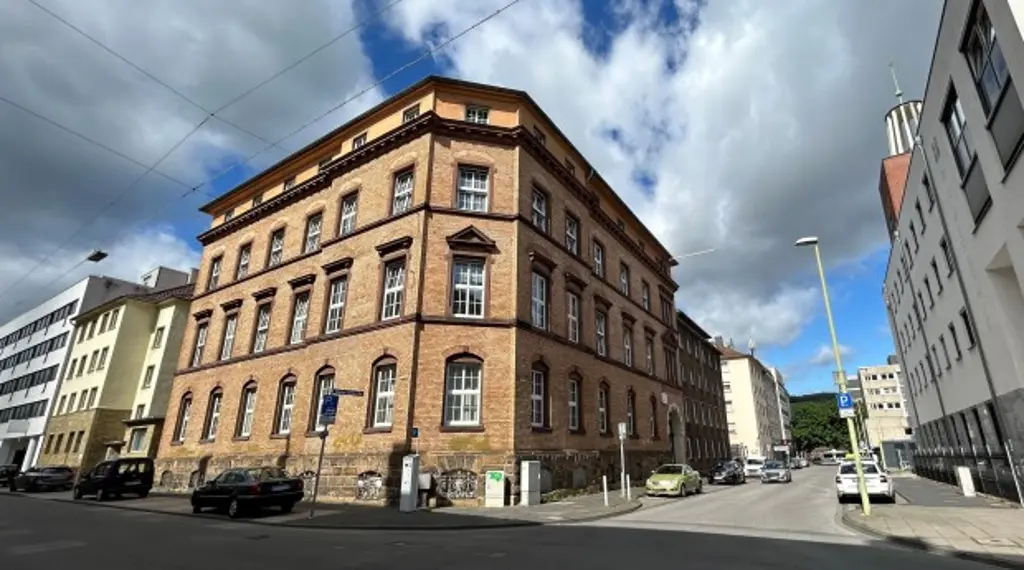 Foto: Ein Gebäude mit älterer brauner Fassade an einer Straßenkreuzung.