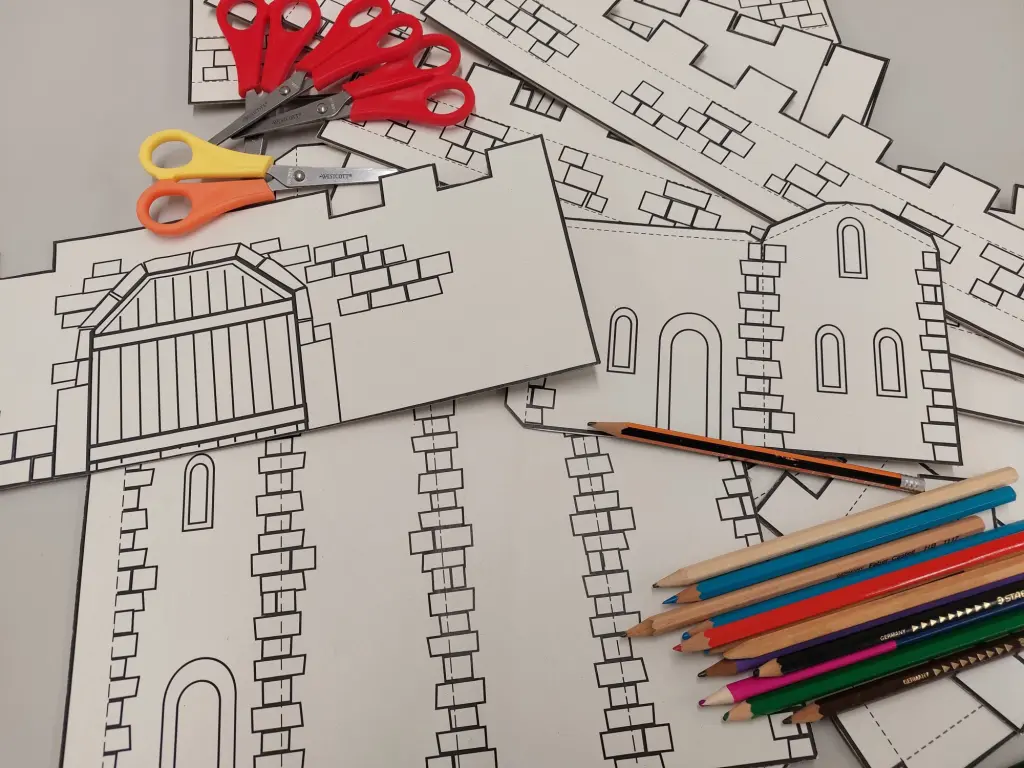 Foto: Mehrere Museumsmauern auf Papier zum Ausmalen neben Buntstiften und Scheren für Kinder.