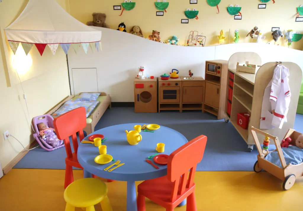 Foto: Ein Raum in einem Kindergarten mit einem kleinen Tisch und einer Spielecke mit vielen verschiedenen Spielzeugen.