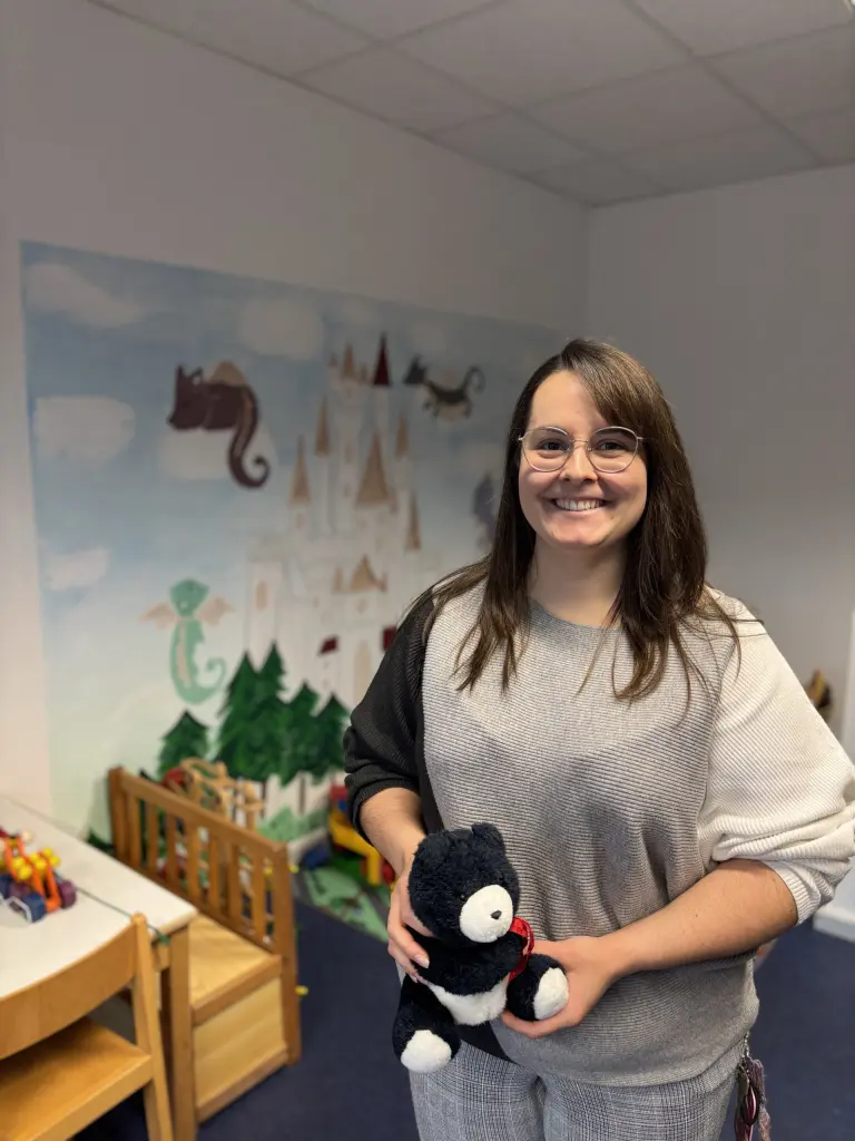 Eine angehende Kollegin mit dem Abschluss Bachelor of Arts in Sozialer Arbeit steht in ihrem B&uuml;ro vor einer Kinderecke. Die Szene vermittelt eine professionelle und zugleich kindgerechte Arbeitsumgebung.