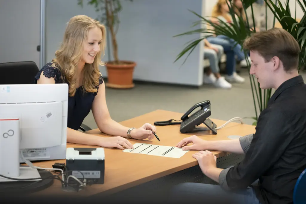 Eine Verwaltungsfachangestellte der Fachrichtung Kommunalverwaltung bespricht gemeinsam mit einem B&uuml;rger im B&uuml;rgeramt ein Antragsformular. Die Szene vermittelt freundlichen Service und kompetente Beratung im &ouml;ffentlichen Dienst.