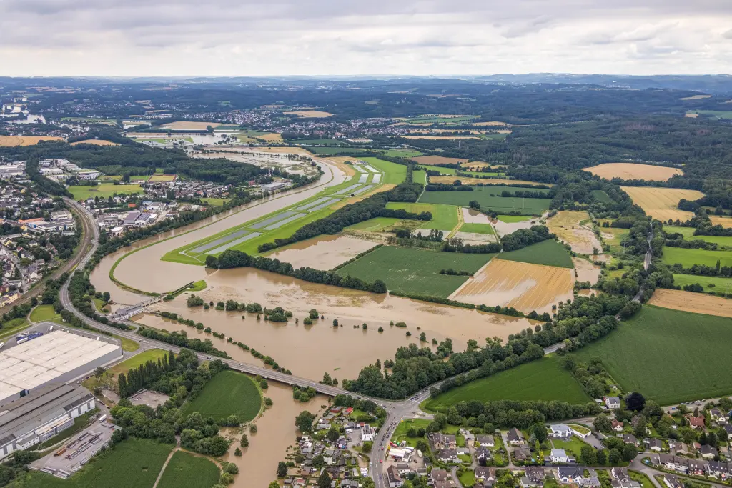 Foto: Eine überflutete Landschaft mit verschlammten Feldern und Straßen aus der Vogelperspektive.