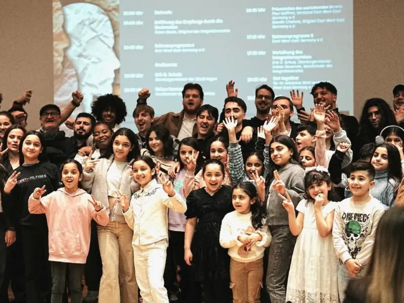 Foto: Eine Gruppe von Kindern und Jugendlichen winkt in die Kamera.