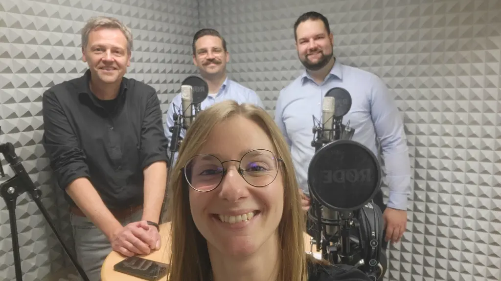 Vier Personen in einem Tonstudio. Zu sehen ist auch Tonequipment.