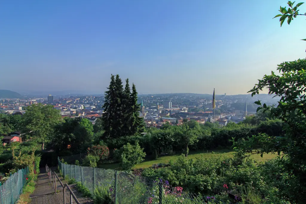 Foto: Im Vordergrund sind Bäume und ein Kleingarten zu sehen, in der Ferne die Dächer der Stadt Hagen.