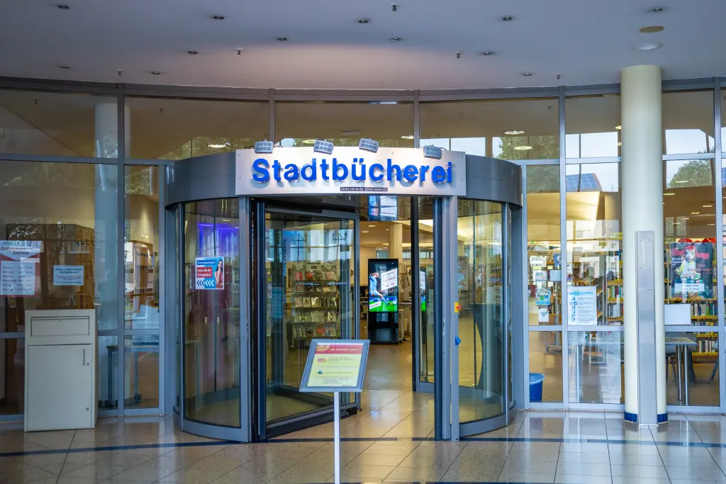 Foto: Der gläserne Eingang der Stadtbücherei mit automatischer Drehtür.