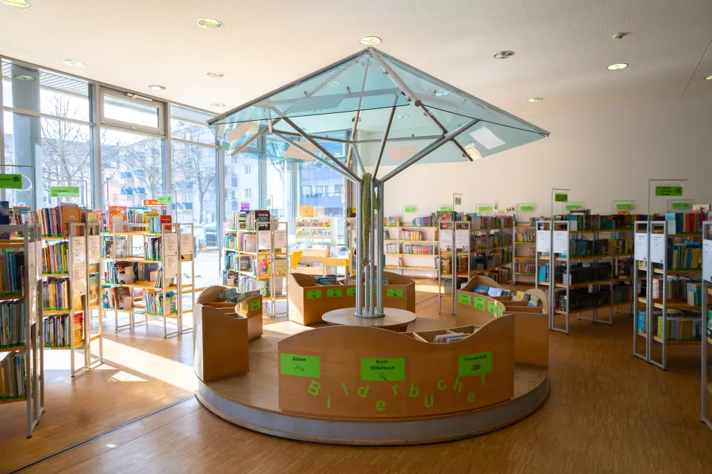Foto: Zu sehen ist die Kinderbücherei in der Stadtbücherei auf der Springe mit einem Rondell und mehreren Bücherregalen.