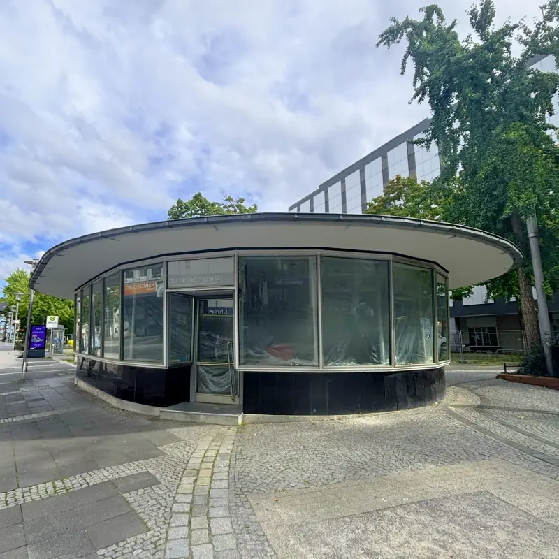 Foto: Ein Pavillon mit zugeklebten Fenstern auf einem großen Platz.