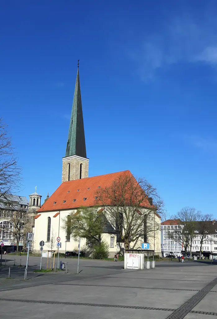 Foto: Zu sehen ist einer Kirche mit Spitzdach auf einem Marktplatz.