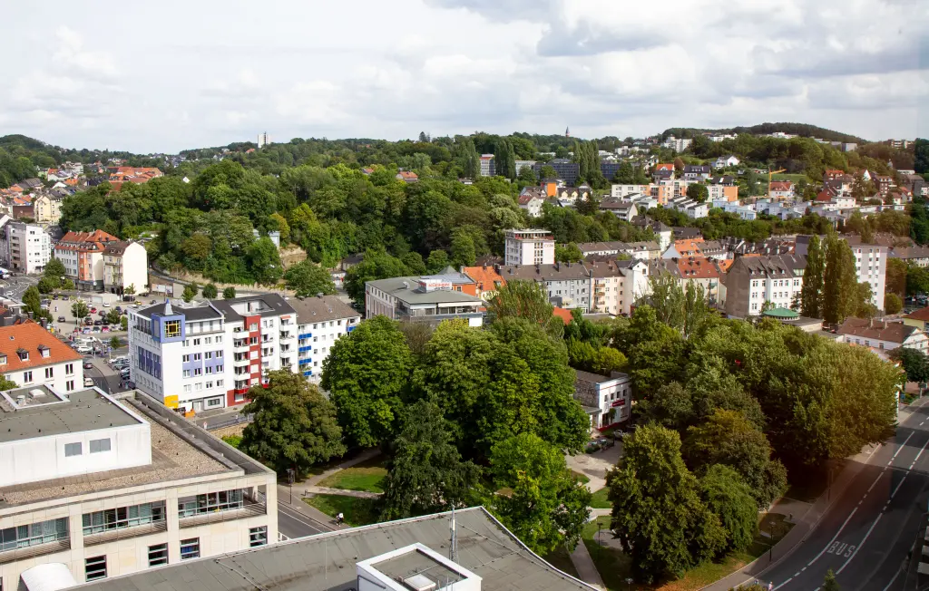 Foto: Das Luftbild eines keinen grünen Parks, am Rand befinden sich Gebäude.