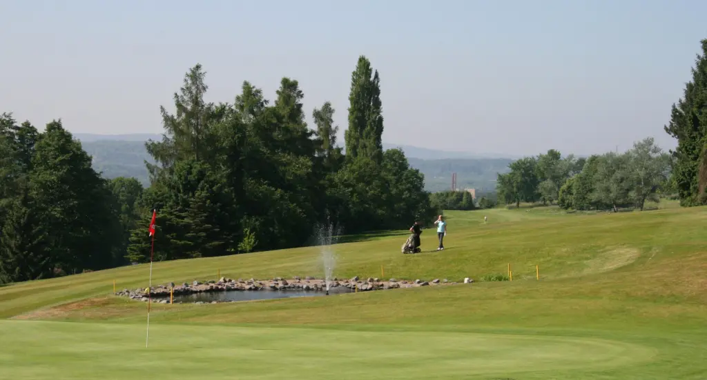Foto: In der Ferne sind zwei Personen auf einem Golfplatz zu sehen.