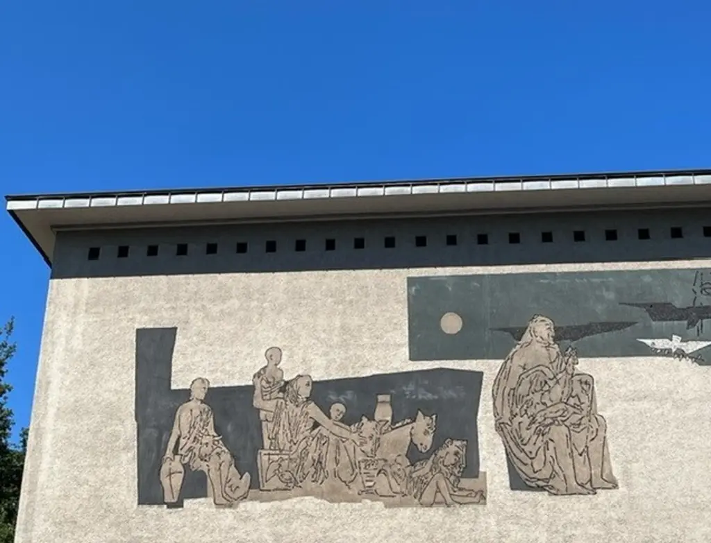 Foto: Die obere Ecke eines hohen Gebäudes, auf dem Wandmalerein zu sehen sind.