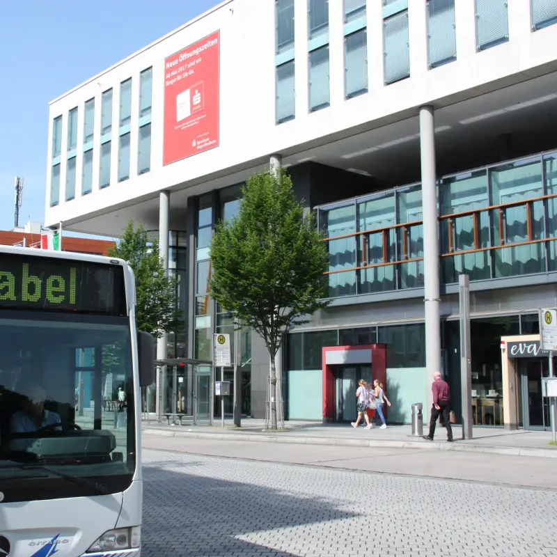 Foto: Ein Bus h&auml;lt an einer Haltestelle gegen&uuml;ber des Sparkassen-Karrees.