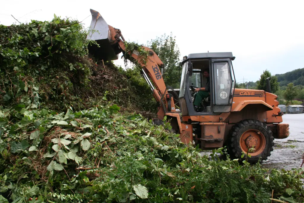 Foto: Aufnahme, eines Baggers, der Abf&auml;lle auf einen Komposthaufen sch&uuml;ttet.