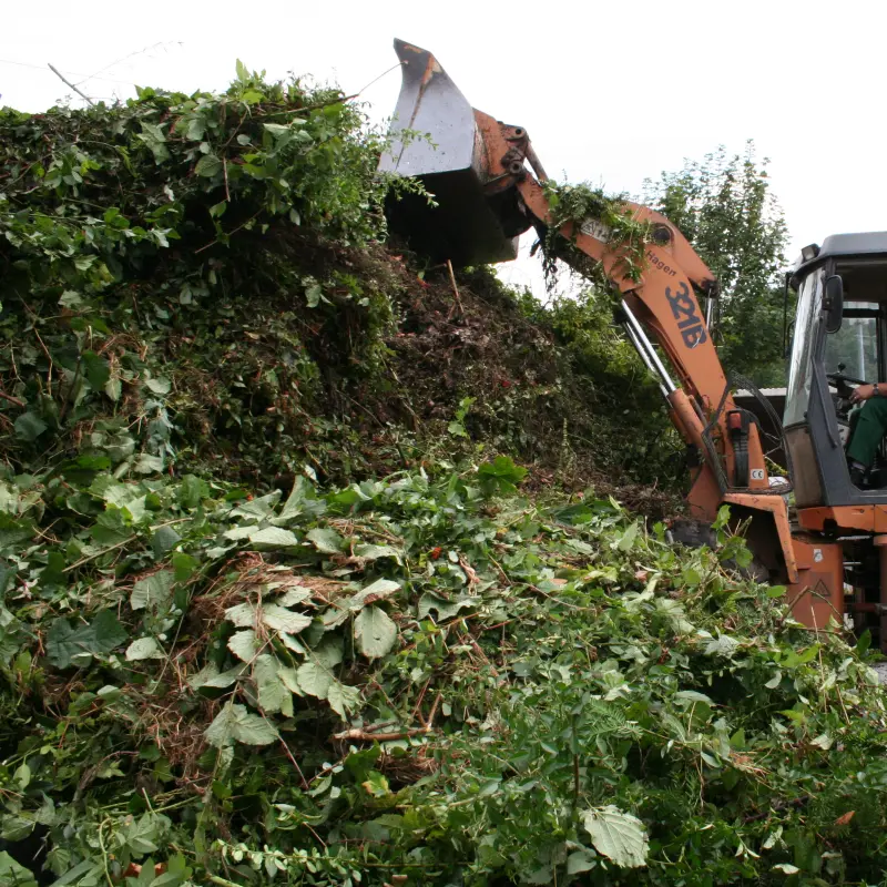 Foto: Aufnahme, eines Baggers, der Abf&auml;lle auf einen Komposthaufen sch&uuml;ttet.