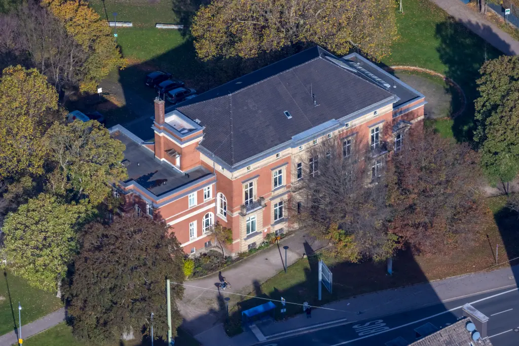 Foto: Luftaufnahme einer großen Villa mit rot-brauner Fassade.