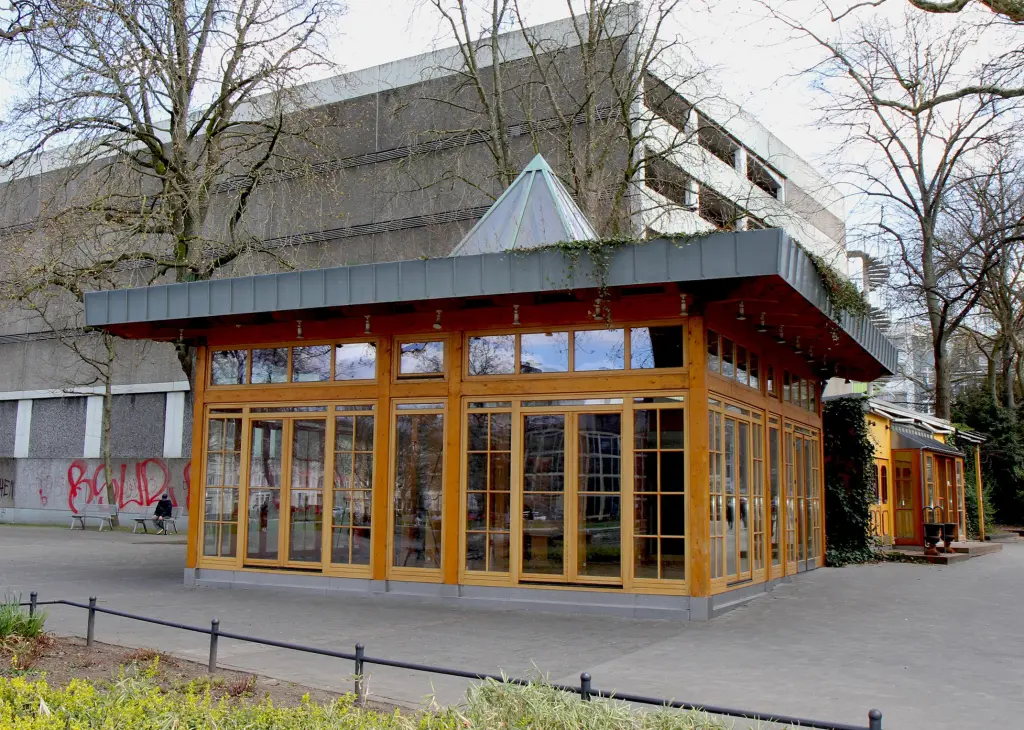 Foto: Die Außenaufnahme eines Cafés. Im Hintergrund befindet sich ein Parkhaus.