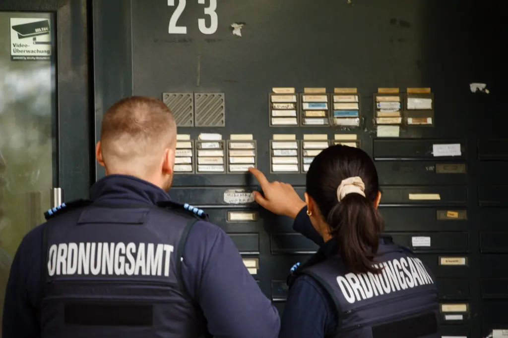 Foto: Zwei Mitarbeitende des Ordnungsamtes stehen an einer Tür und drücken auf ein Klingelschild.