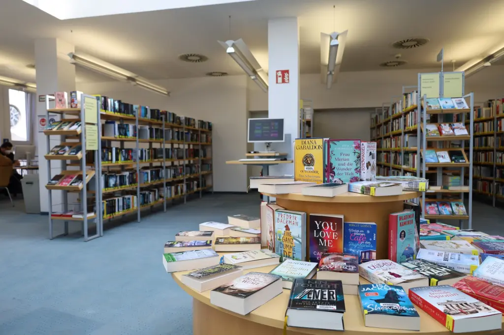 Eine Innenaufnahme einer Bücherei, im Vordergrund ein Büchertisch.