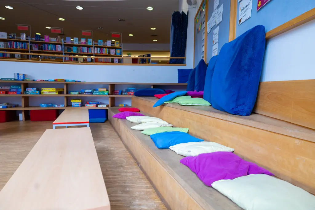 Foto: Viele bunte Sitzkissen liegen auf einer kleinen Lesetreppe in der Stadtbücherei.