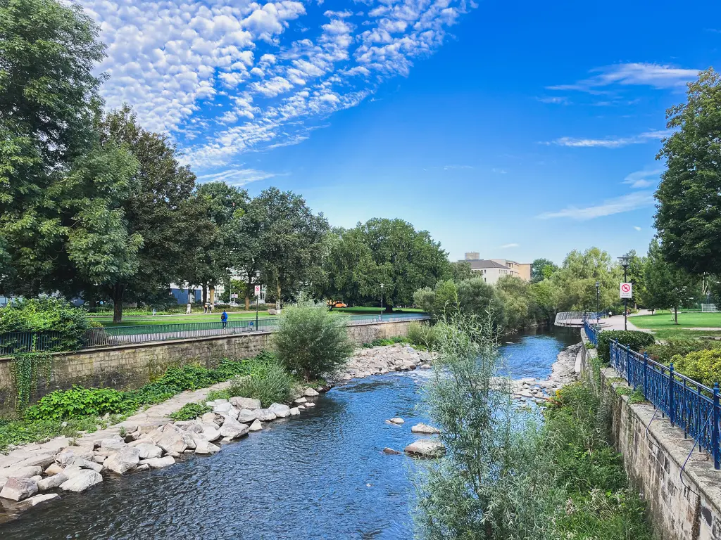 Foto: Grünflächen umgeben unter blauem Himmel die Volme.