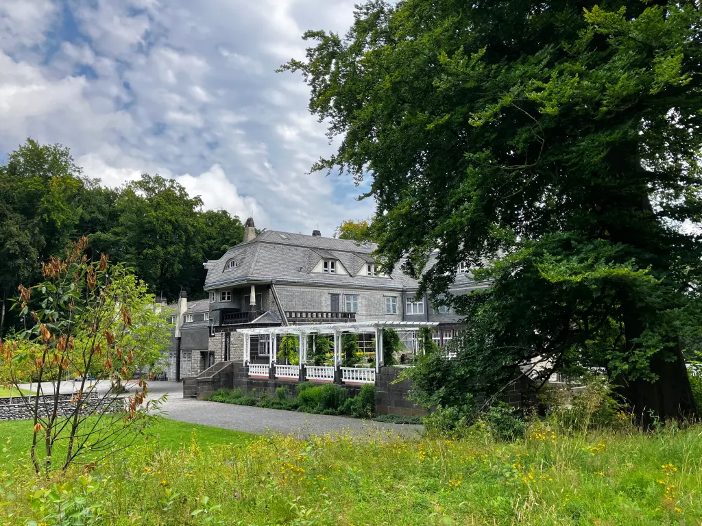 Die Villa Hohenhof umgeben von B&auml;umen und Wiesen.