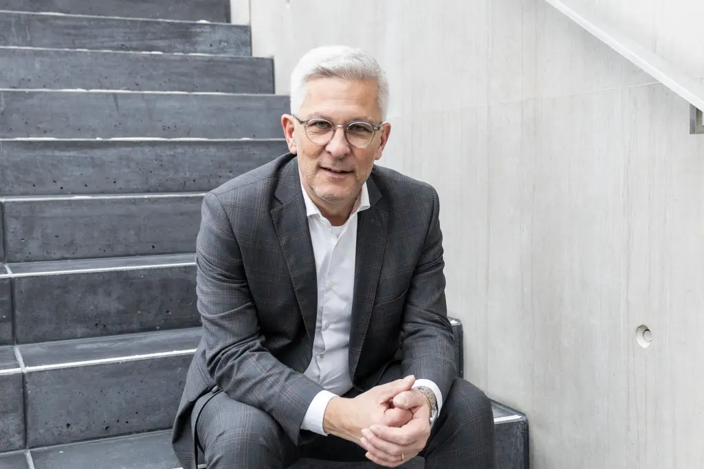 Foto: Oberbürgermeister Erik O. Schulz sitzt auf einer Treppe und verschränkt die Hände ineinander.