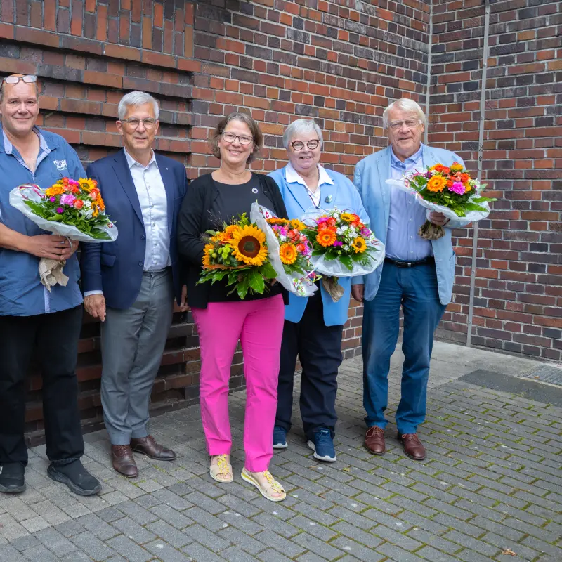 Foto: Auf dem Foto sieht man sechs Personen. Fünf Personen halten einen Blumenstrauß in der Hand.