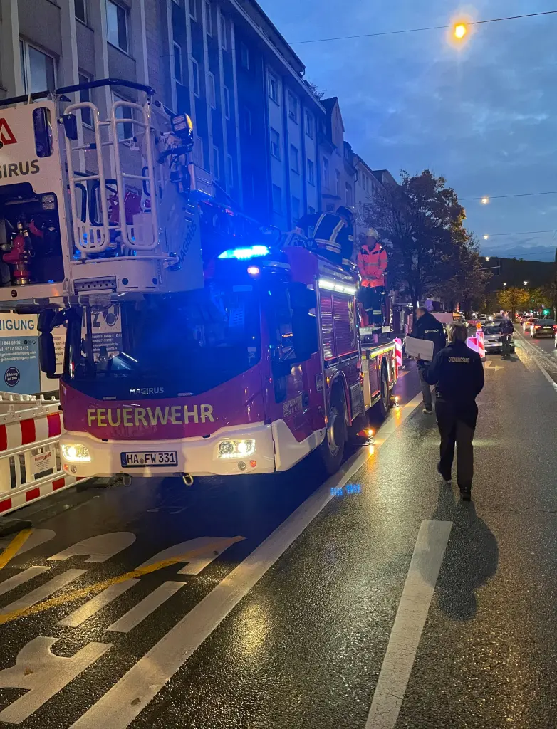 Foto: Ein Feuerwehr mit Drehleiter steht im Dämmerlicht auf einer großen Straße.