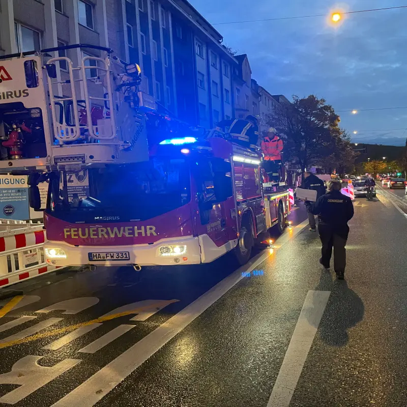 Foto: Ein Feuerwehr mit Drehleiter steht im Dämmerlicht auf einer großen Straße.