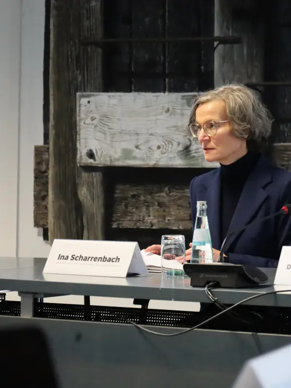 Foto: Ina Scharrenbach und Dennis Rehbei sitzen nebeneinander in einer Pressekonferenz, Frau Scharrenbach spricht in ein Mikrofon.
