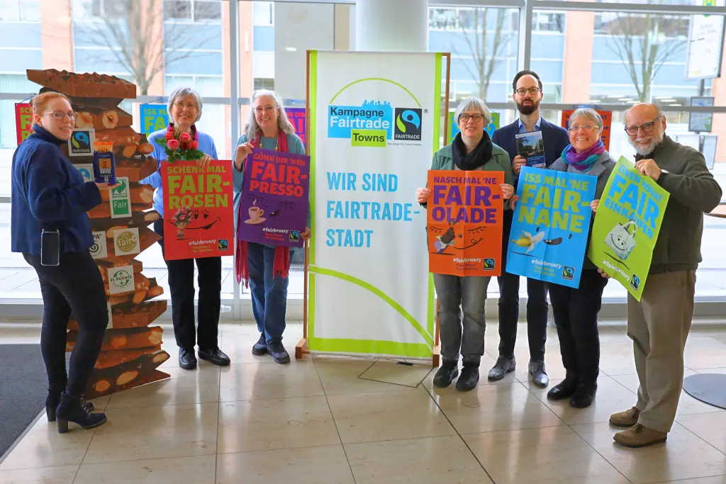 Gruppenbild: Beteiligte der Steuerungsgruppe Fair Trade Town Hagen mit bunten Plakaten und einem Banner zum Fairbruary.
