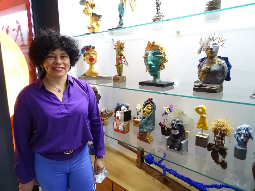 Foto: Eine Frau steht vor einer Vitrine mit Skulpturen.