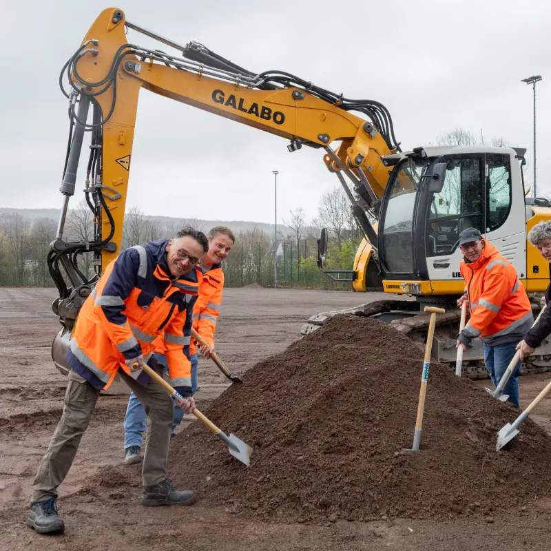 Foto: F&uuml;nf M&auml;nner stehen mit Spaten in den H&auml;nden neben einem Erdhaufen.