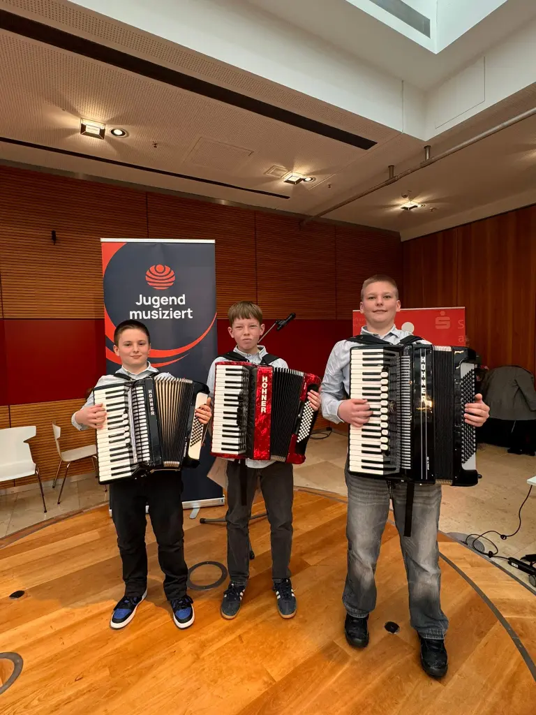 Foto: Drei Jungen stehen mit ihren Akkordeons in einem Raum.