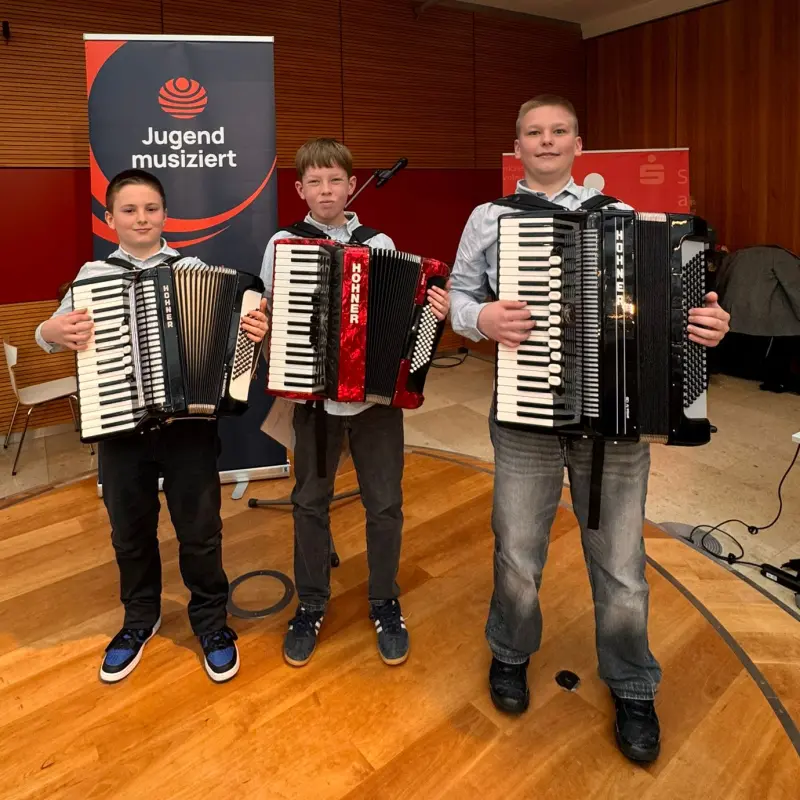 Foto: Drei Jungen stehen mit ihren Akkordeons in einem Raum.