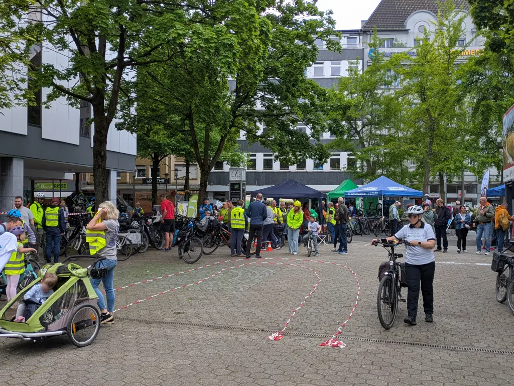 Foto: Viele Menschen - mit und ohne Fahrraf - tummeln sich in der Hagener Innenstadt. Einige haben gelbe Warnwesten an, auf dem Boden ist mir rot-wei&szlig;em Absperrband ein Fahrrafparcours aufgebaut worden.