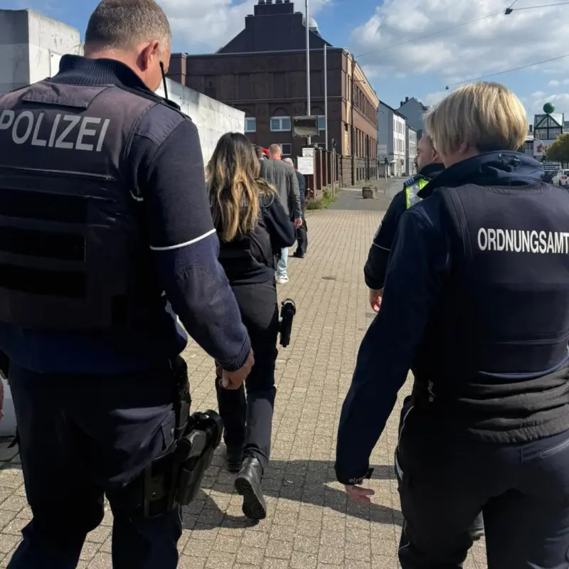 Foto: Mitarbeitende von polizei und Ordnungsamt laufen auf einem B&uuml;rgersteig auf eine H&auml;suerzeile zu.
