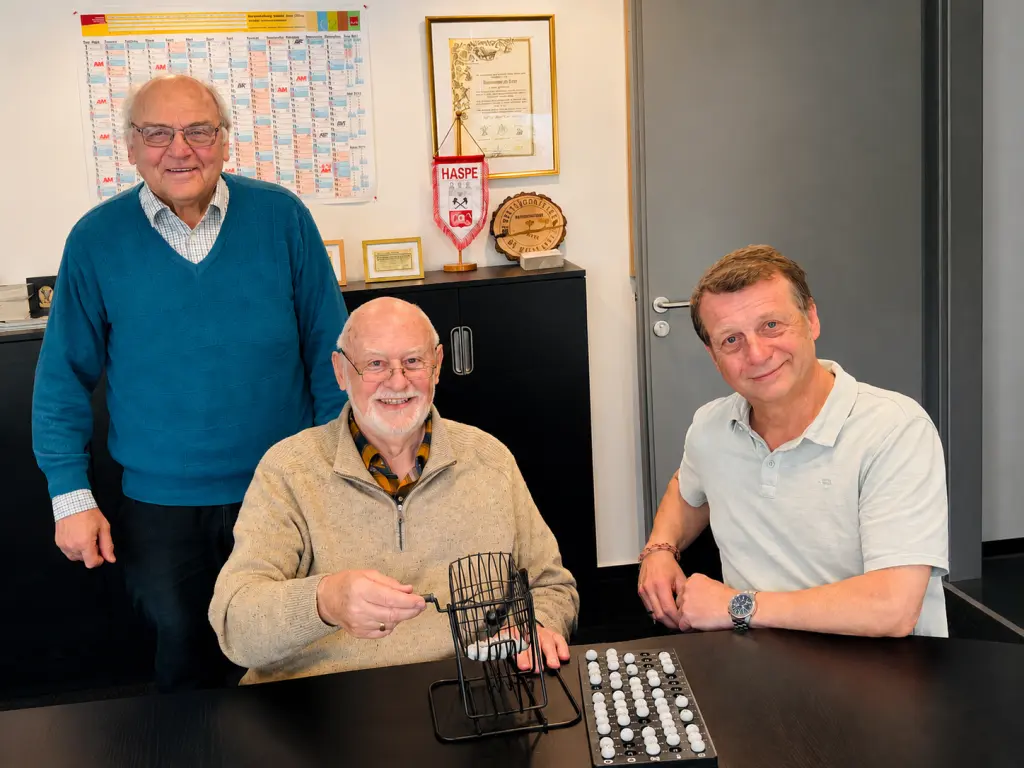 Foto: Horst Wisotzki steht neben Dieter Friedhoff und Frank Henkes, die an einem Tisch vor einer Lostrommel sitzen.