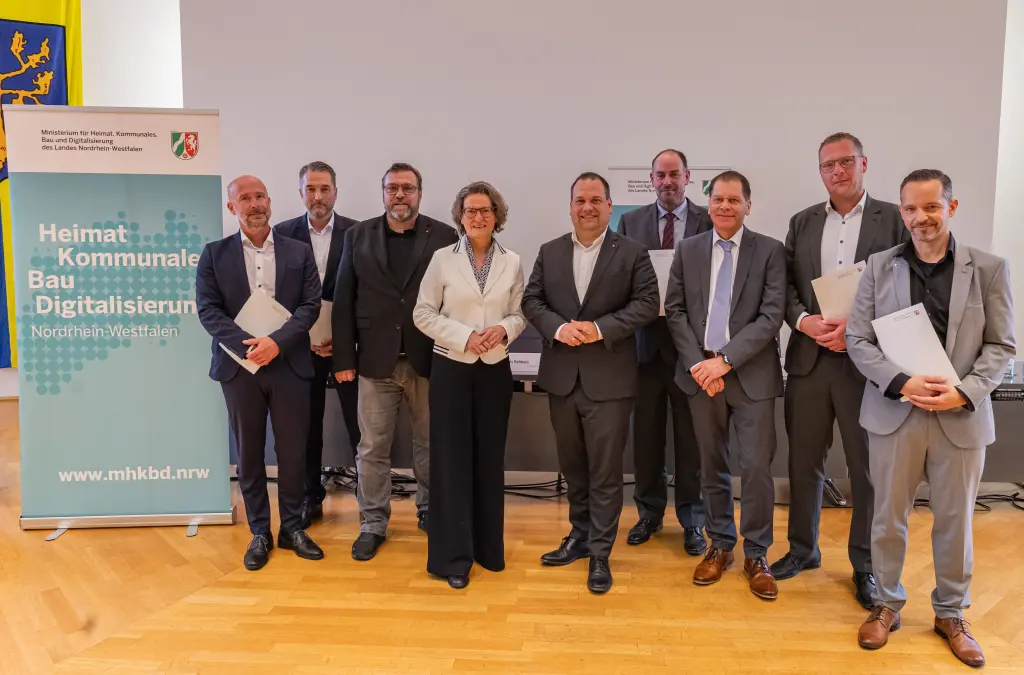 Foto: Die in der Bildzeile aufgef&uuml;hrten Personen stehen nebeneinander und halten den unterezichneten Vertrag in den H&auml;nden.