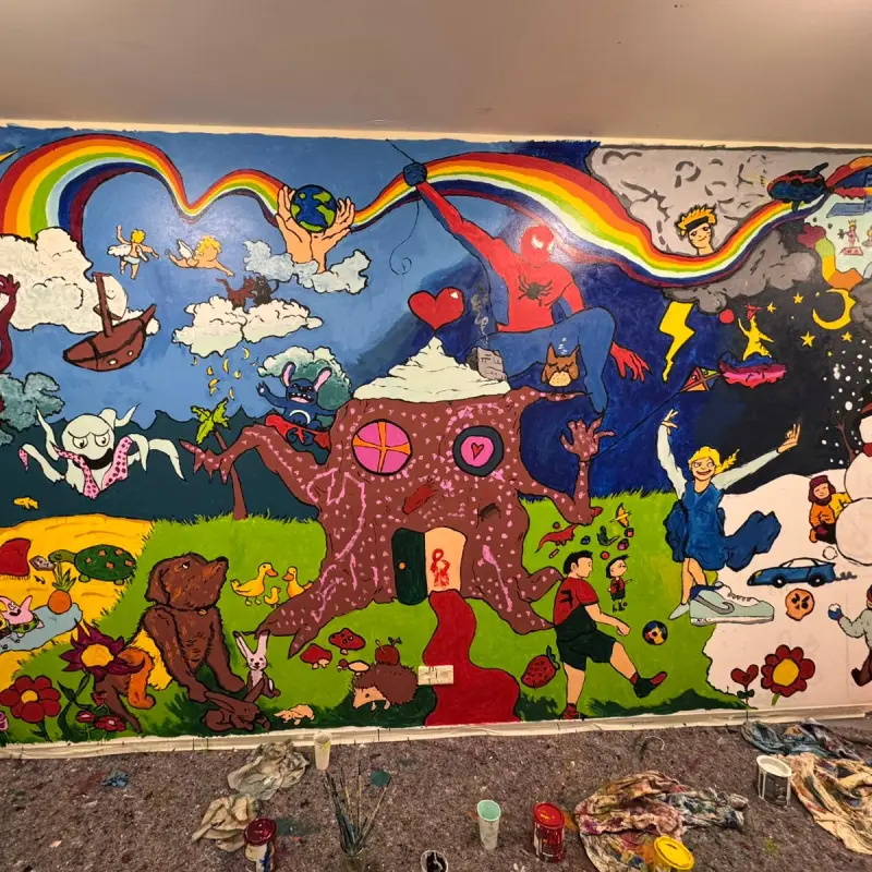 Foto: Eine Wand mit vielen bunten Kunstwerken, z.B. ein Regenbogen, ein Haus, Tiere und verschiedene Comcic- bzw. Zeichentrickfilmhelden
