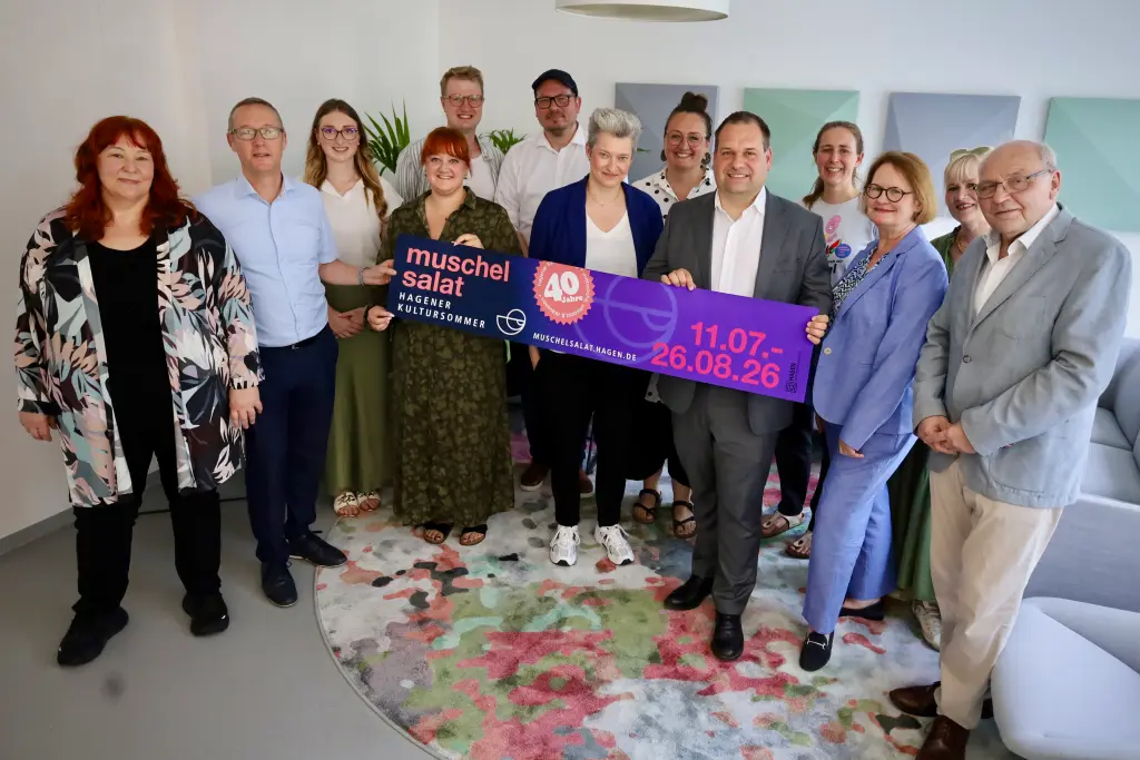 Foto: Die oben genannten Personen halten ein Banner in den H&auml;nden, auf dem Werbung f&uuml;r den 40. Muschelsalat gemacht wird.