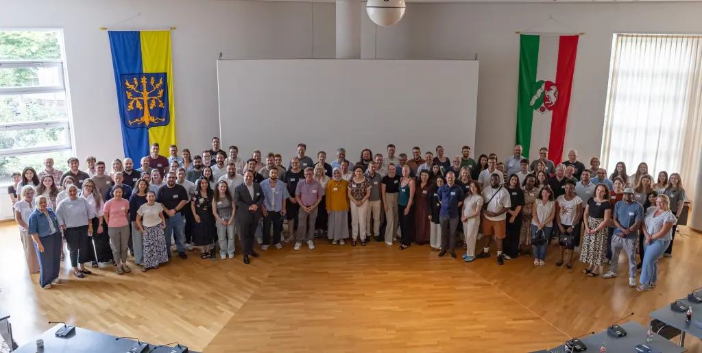 Foto: Die neuen Mitarbeitenden der Stadtverwaltung sowie Oberb&uuml;rgermeister Dennies Rehbein haben sich im Ratssaal f&uuml;r ein Foto aufgestellt.