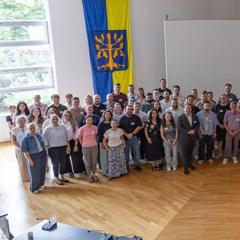 Foto: Die neuen Mitarbeitenden der Stadtverwaltung sowie Oberb&uuml;rgermeister Dennies Rehbein haben sich im Ratssaal f&uuml;r ein Foto aufgestellt.
