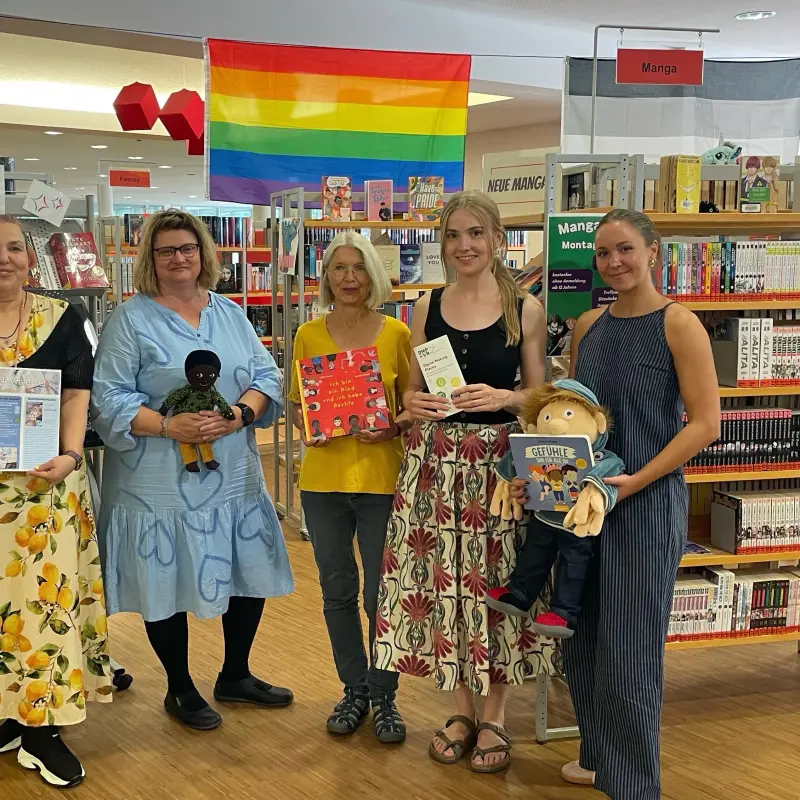 Foto: Die in der Bildzeile gennnten Personen stehen nebeneinader und halten B&uuml;cher sowie Kuscheltiere in den H&auml;nden.