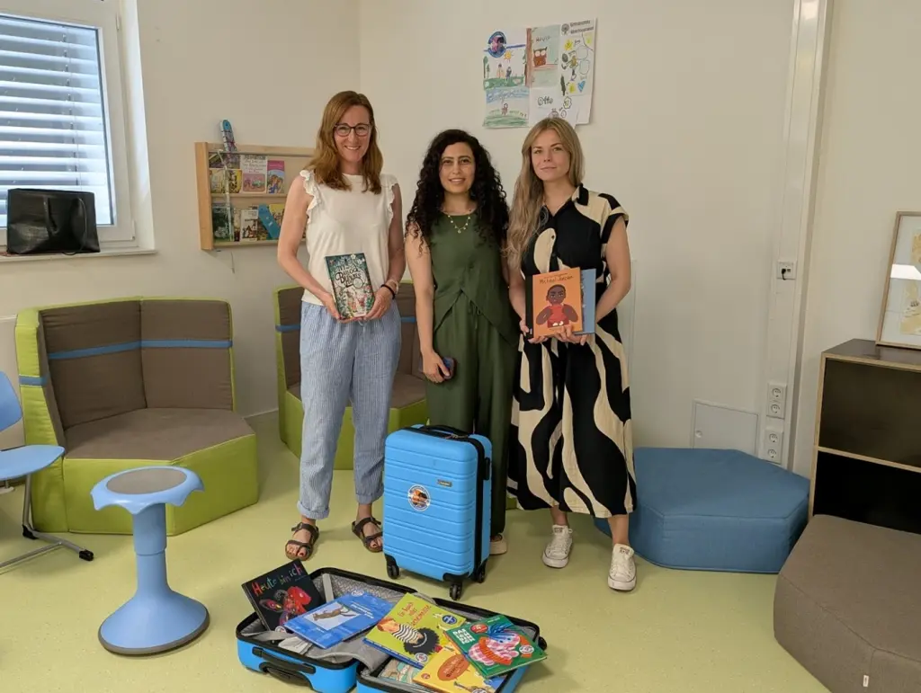 Foto: Die oben aufgef&uuml;hrten Personen stehen hinter zwei blauen B&uuml;cherkoffern und halten zum Teil auch B&uuml;cher in der Hand.
