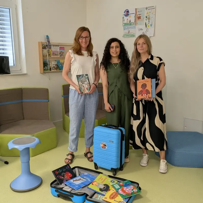 Foto: Die oben aufgef&uuml;hrten Personen stehen hinter zwei blauen B&uuml;cherkoffern und halten zum Teil auch B&uuml;cher in der Hand.