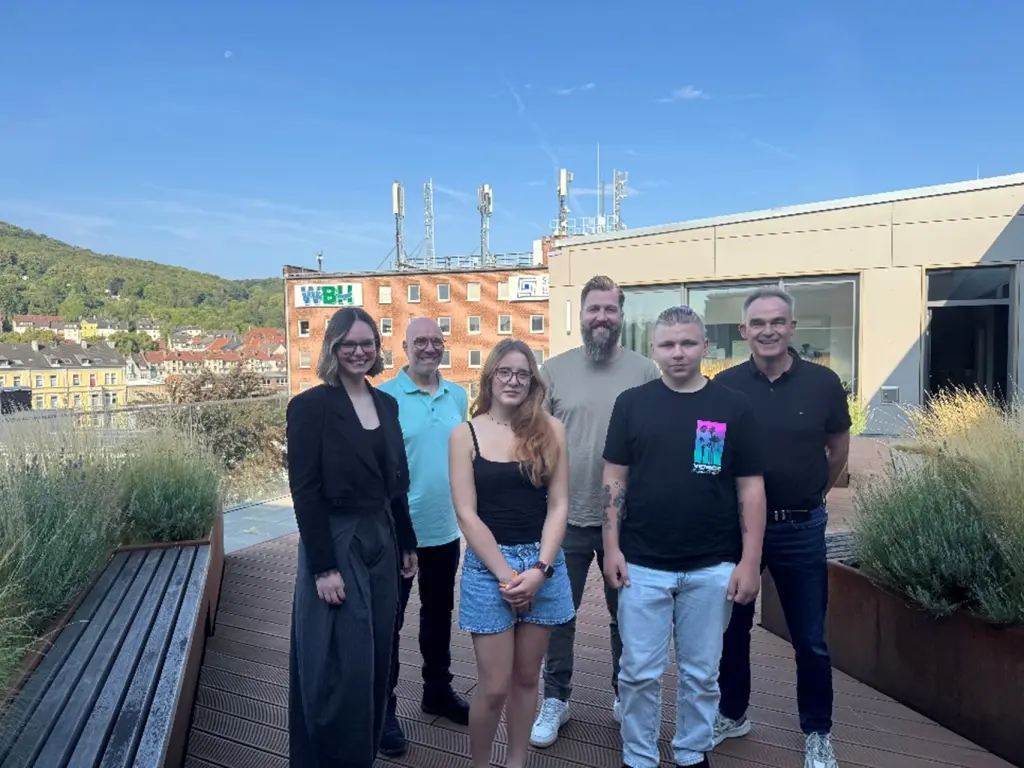 Foto: Die oben genannten Personen stehen auf einer Dachterrasse nebeneinander.